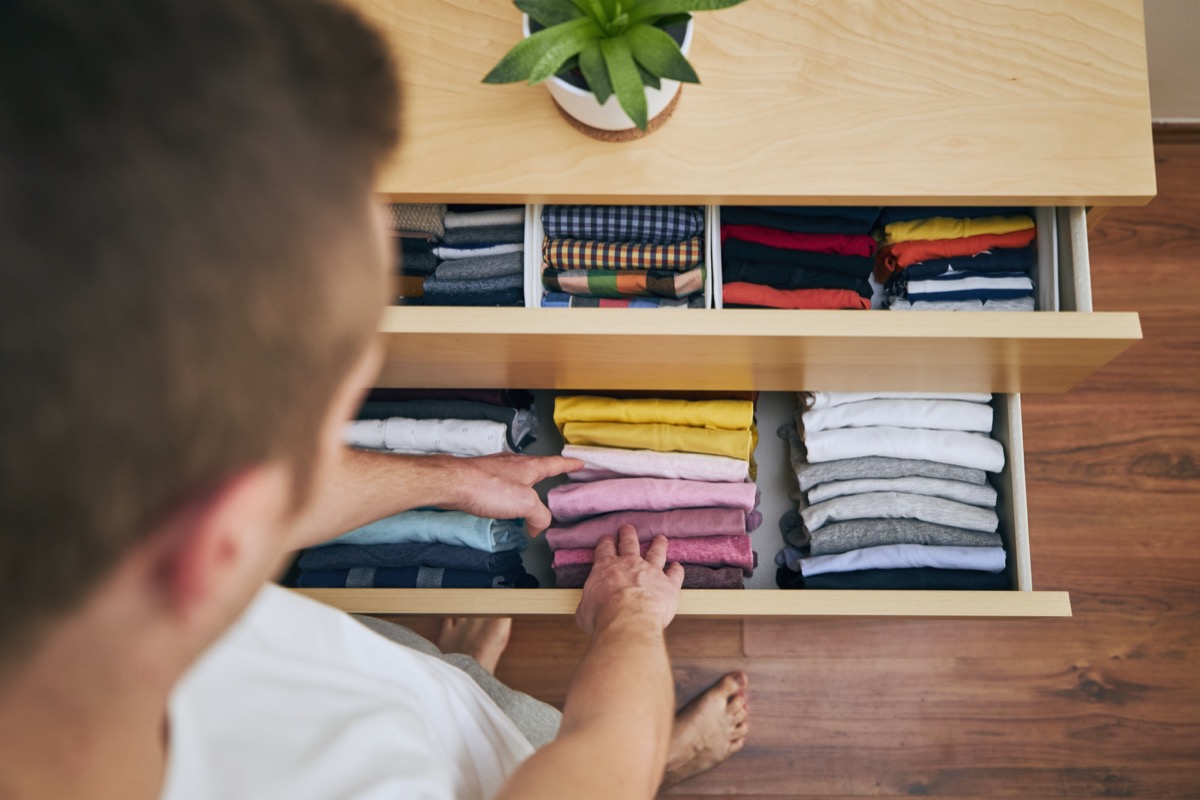 Organisation et nettoyage de la maison.  Homme préparant des t-shirts pliés dans le tiroir.